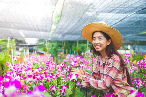 Asian girl, owner of orchid flower farm export Borrow smiling, wearing a hot sun hat © SUPERMAO