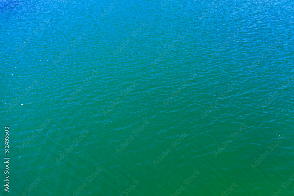 Obraz premium aerial view of the texture of the surface of turquoise water with sun reflections