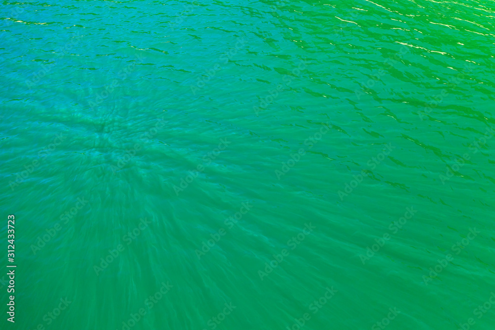 aerial view of the texture of the surface of turquoise water with sun reflections