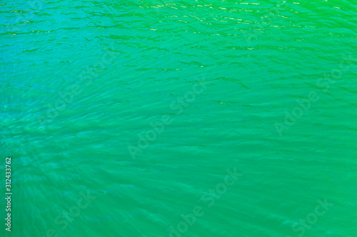 aerial view of the texture of the surface of turquoise water with sun reflections