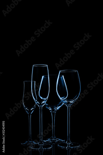 Glassware selection with wine, champagne and liquour glasses toned in classic blue on the dark background.. Fine cristal glassware concept. Vertical