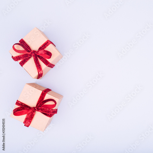 Craft boxes with dark red ribbon bows. Holiday, Christmas, New Year and Valentine day eco-friendly wrapping concept. Trendy minimalistic flat lay design background. Square © Ekaterina_Molchanova