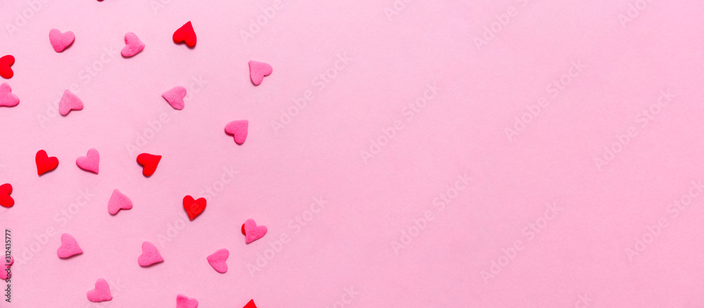 Two tone heart sprinkles on the solid pink background. Romance, love, Valentines and mother's day concept. Flat lay, horizontal wide screen banner format with place for text