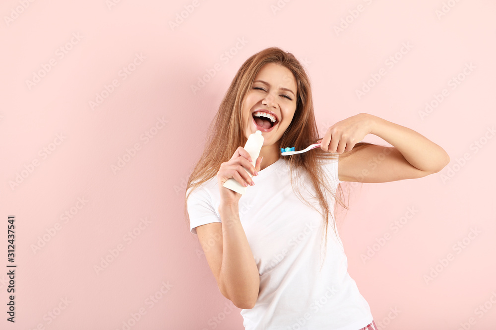 Young woman using tube of tooth paste as microphone on color background Young woman using tube of tooth paste as microphone on color background