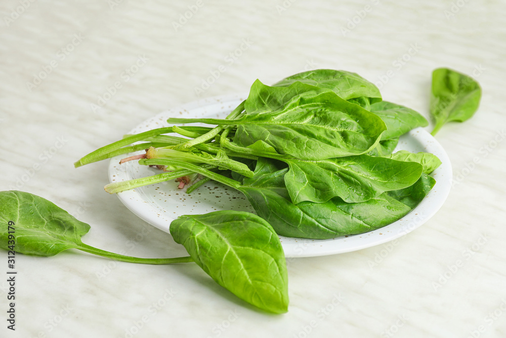 Plate with fresh green spinach on table