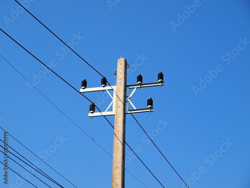 New electricity poles and high voltage cables on the poles Replacing the electric pole With a new set of arms and insulators to support the growth of urban communities On the blue sky background