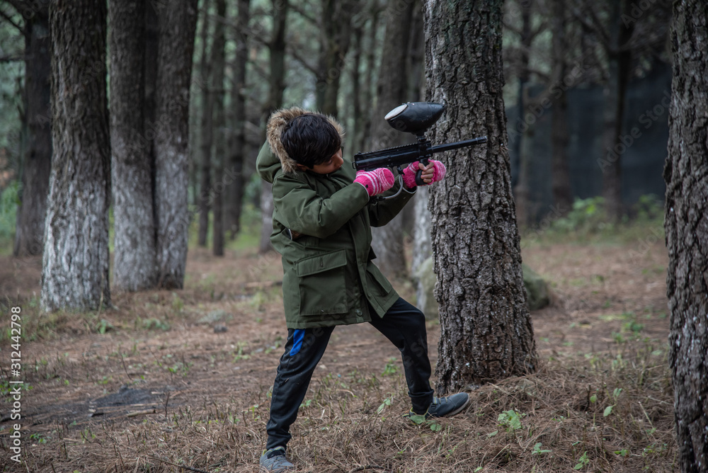Fototapeta premium boy with green jacket playing gotcha in the woods among trees