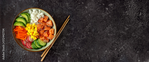 Top view of poke bowl with salmon and avocado on dark background photo