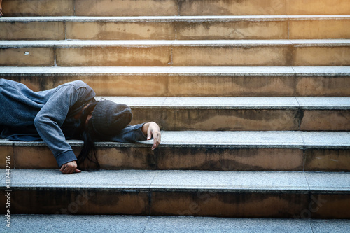 The poor homeless person lay at the public staircase. No place to go. © SUPERMAO
