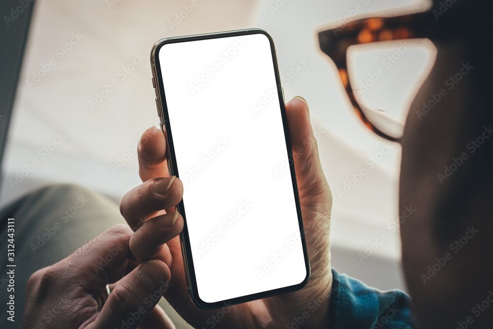 Mockup image blank white screen cell phone.man hand holding texting using mobile on sofa at coffee shop.background empty space for advertise text.people contact marketing business,technology
