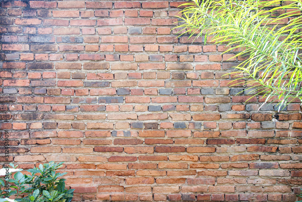 Vintage brick wall texture in horizontal line patterns with green leaves of tree branch for background
