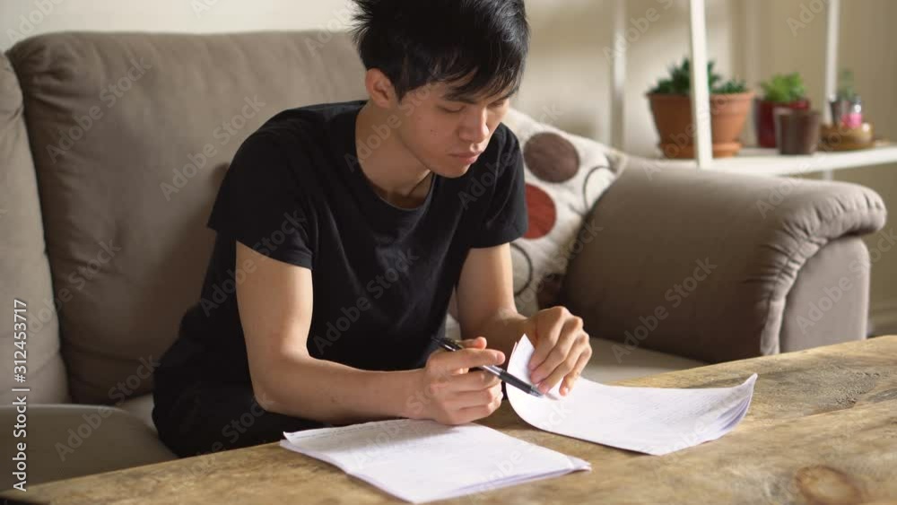 Asian College Student Doing Homework in Living Room Asian College Student Doing Homework in Living Room