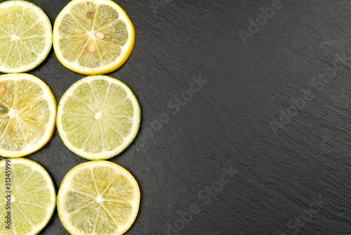 Top view of lemon and lime on black plate with black background