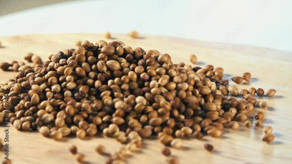 Coriander Seeds Rotating on a Wooden Board Coriander Seeds Rotating on a Wooden Board
