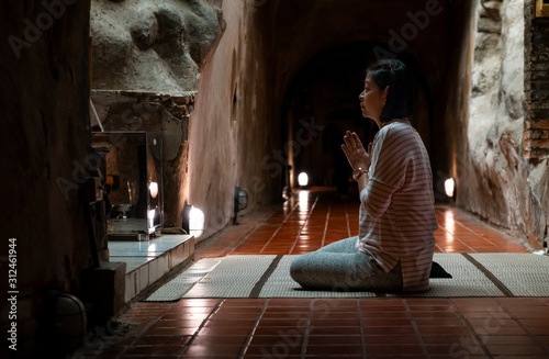 woman praying to old buddha