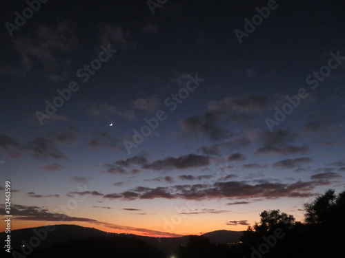  moon and first star in sun set sky over mountains