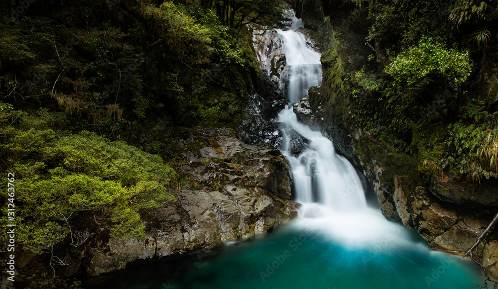 Milford Sound, New Zealand - Beautiful waterfall on the road between Te Anau and Milford Sound Milford Sound, New Zealand - Beautiful waterfall on the road between Te Anau and Milford Sound