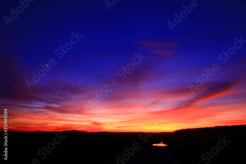 Very colorful clouds in dramatic sky. Romantic sunset at the countryside.