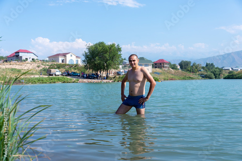 A young man standing in the water on the lake