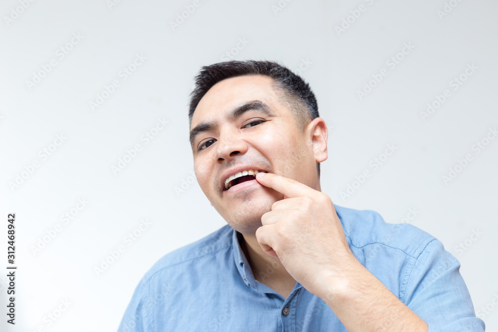Portrait of a man in blue shirt showing teeth on a white background Portrait of a man in blue shirt showing teeth on a white background