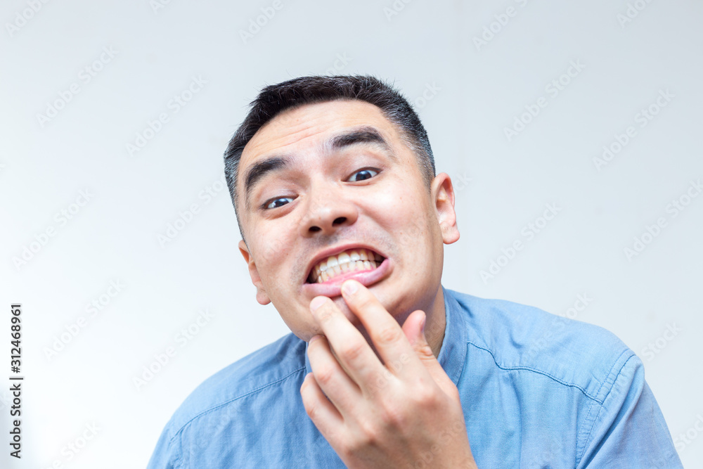 Portrait of a man in blue shirt showing teeth on a white background Portrait of a man in blue shirt showing teeth on a white background