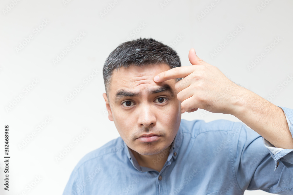 Obraz premium Portrait of a man in a blue shirt looking at the forehead of wrinkles on white background