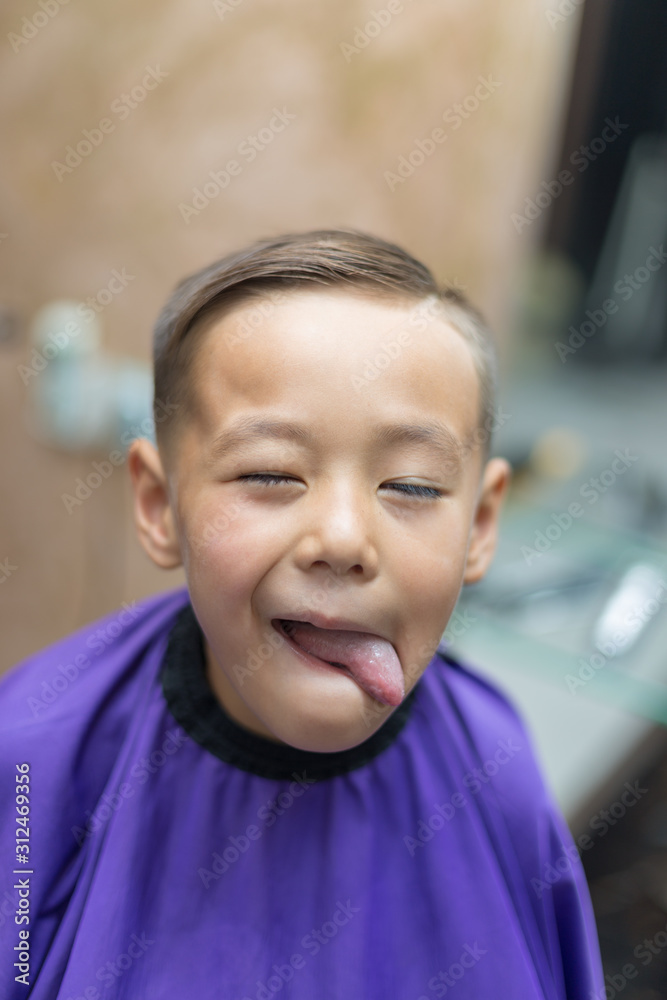 Close-up portrait of an attractive handsome smiling little boy looking at camera after haircut. Hair. Beautiful boy. Six year old boy smiling and having fun