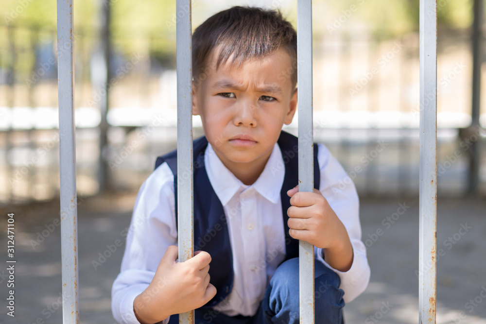 Obraz premium schoolboy holds cell and hopes for freedom or makes fun of the concept of life imprisonment