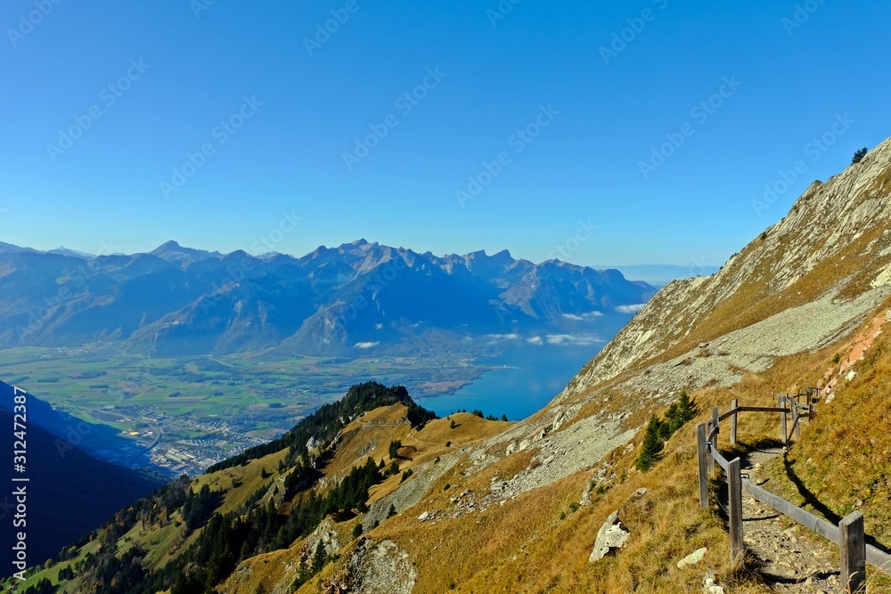Obraz premium Trail on the peak of Rochers-de-Naye with Lake Geneva and gorgeous view of gigantic mountains as background.