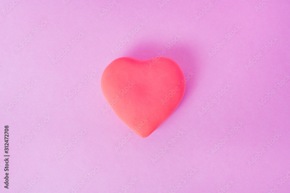 red heart on a pink background. the heart is located in the center of the frame..