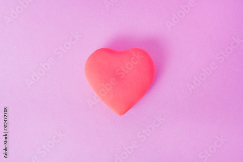 red heart on a pink background. the heart is located in the center of the frame..