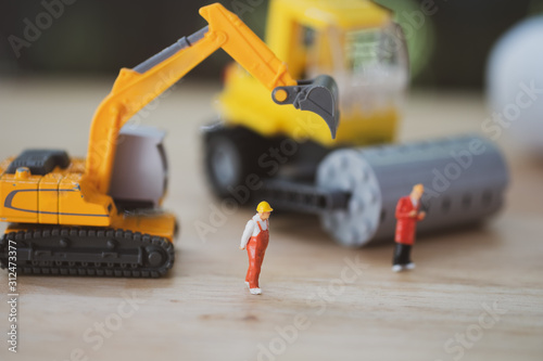 Miniature people : Worker team with yellow construction machinery models