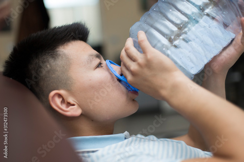 A man drinks water from a five-liter plastic bottle