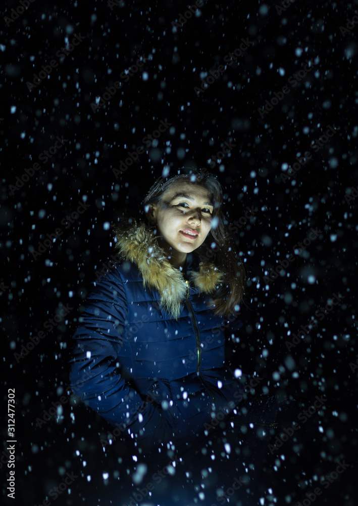 young girl at night in jackets on the background of snowfall young girl at night in jackets on the background of snowfall