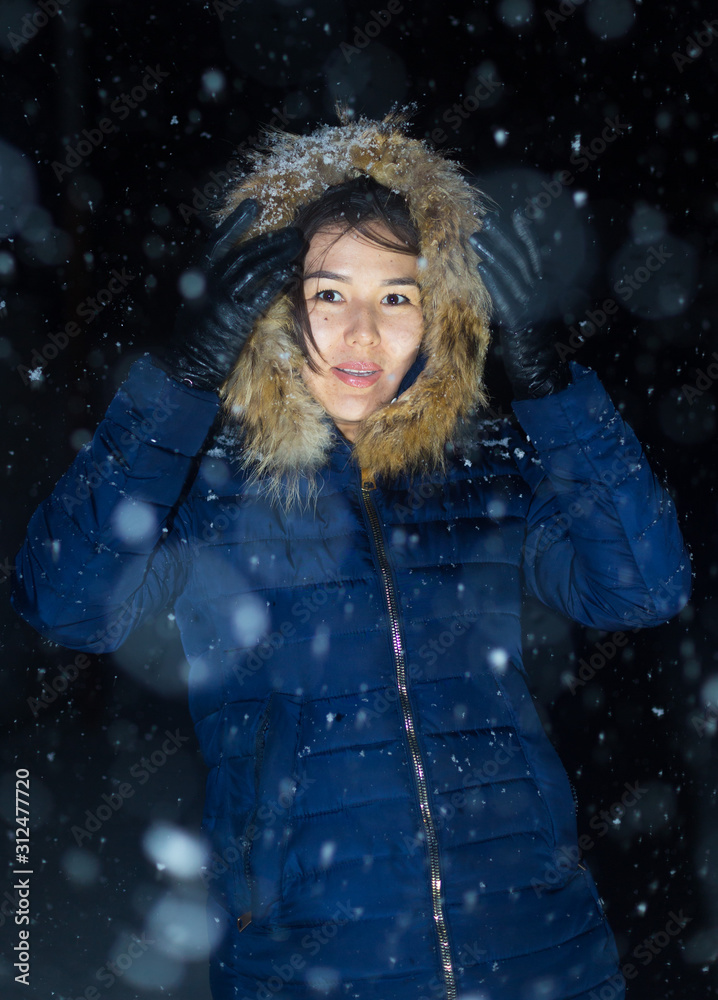 young girl at night in jackets on the background of snowfall young girl at night in jackets on the background of snowfall