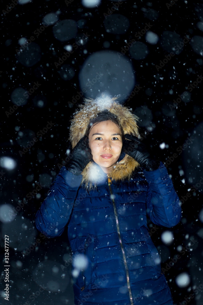 young girl at night in jackets on the background of snowfall young girl at night in jackets on the background of snowfall