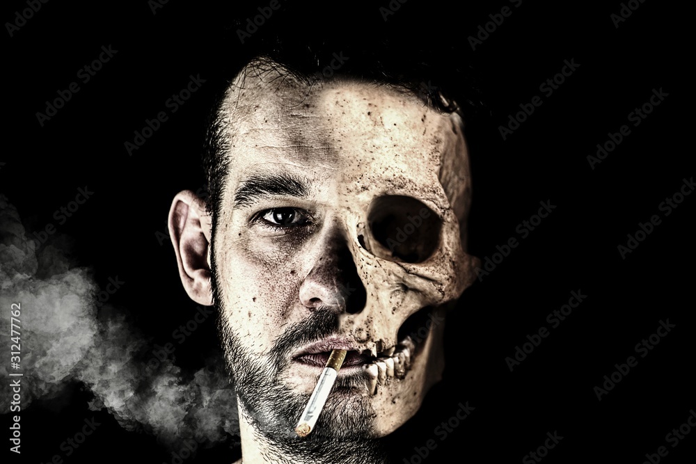 Half male face and half skull. There is a burning cigarette in his mouth,  from which smoke comes. Double face. Stock Photo