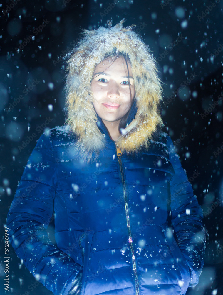 young girl at night in jackets on the background of snowfall young girl at night in jackets on the background of snowfall