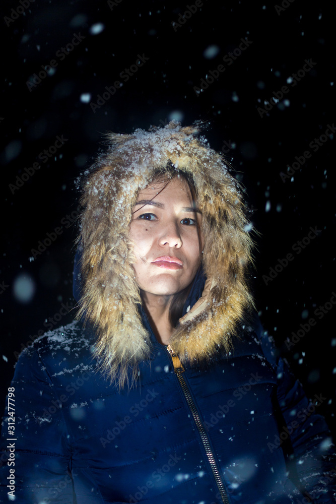 young girl at night in jackets on the background of snowfall young girl at night in jackets on the background of snowfall