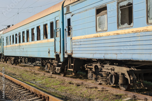 Vandalism on the railway. Vandalism concept. Train vandalism. Broken windows of blue old rusty train. Broken train compartments. Abandoned train car doorway and window detail.