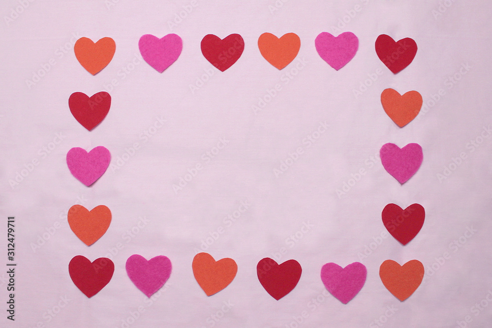 Frame of red, orange and pink hearts on a pink background. Empty space in the center for text and copy. Stock photo for valentine's day