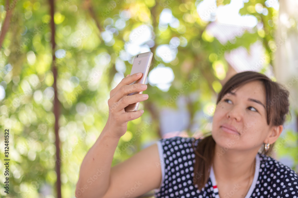 Happy young woman with hair taking pictures on the phone. Cheerful attractive woman in a blue pea shirt posing for a selfie. Social media concept Happy young woman with hair taking pictures on the phone. Cheerful attractive woman in a blue pea shirt posing for a selfie. Social media concept