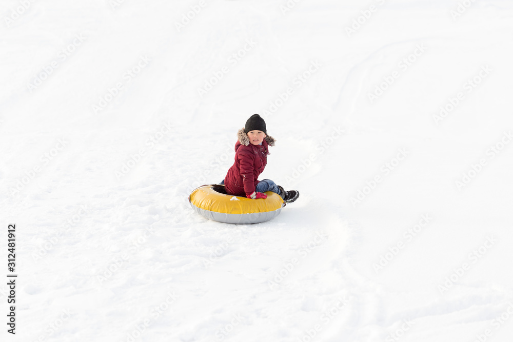Brave child in red jackets, a trip in the winter from the mountains to tubing. He has an inflatable chamber. It slides quickly through the snow.