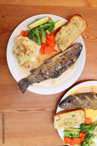 Fish dish - wood oven baked or roasted trout fish served with saute vegetables and mashed potato with copy space. Family meal