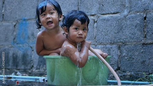 Two Baby girl bathed in a basin. Happy laughing baby taking a bath and playing outdoor. baby in little basin