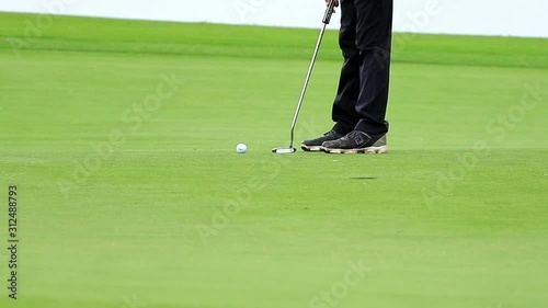 golfer putting a golf ball on green