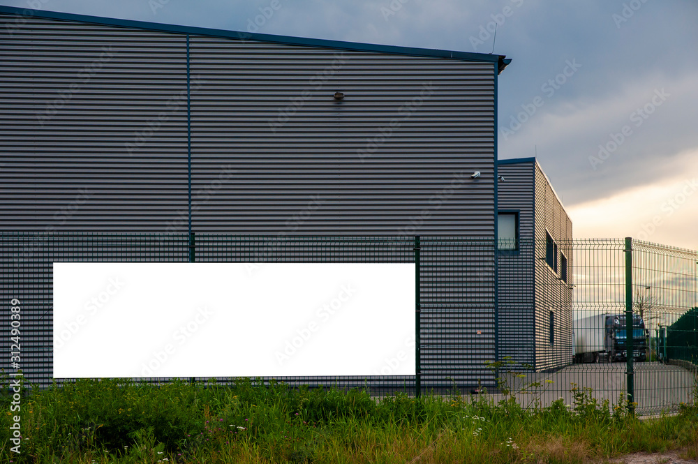Blanks white banner for advertisiement mounted on the fence of the warehouse. Truck is waiting for loading