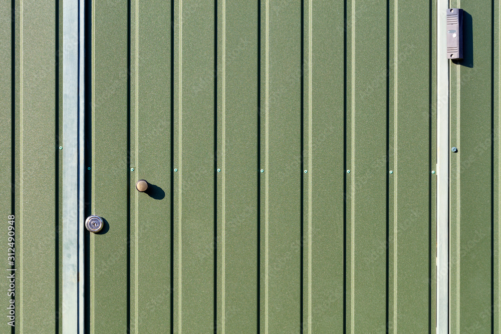 Green metal fence and doors made of corrugated steel sheet with