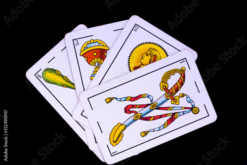 some cards from the spanish deck for playing cards games and gambling on a black background