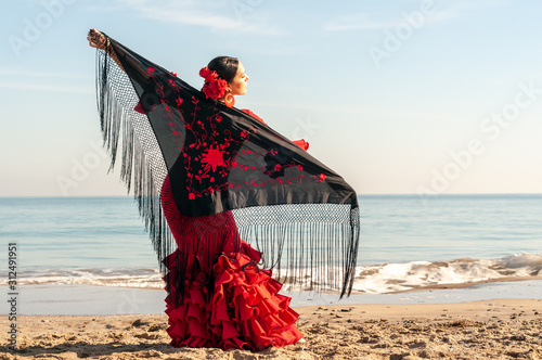 Young Spanish woman dancing flamenco on the beach photo